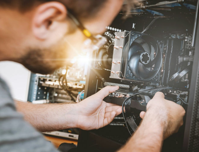 Τεχνικός σε service υπολογιστών desktop με ανοιχτό πύργο και καλωδιώσεις